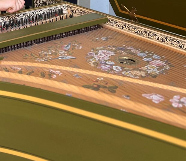 Klangboden eines flämischen Cembalos mit feiner Blumenmalerei und vergoldeter Schallrose im grün gefassten Gehäuse.