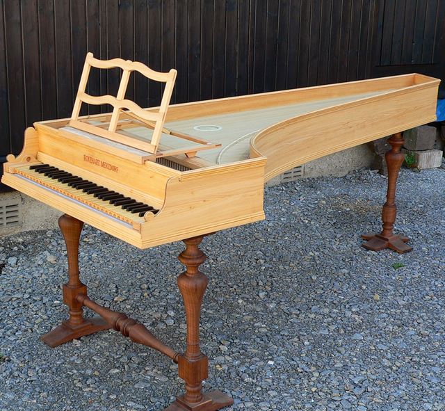 Italienisches Cembalo aus hellem Holz mit schlichtem Gehäuse auf gedrechseltem Untergestell.
